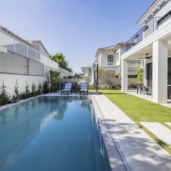 בריכת שחייה מבטון בגינת חצר של בית קרקע פרטי בצבע לבן